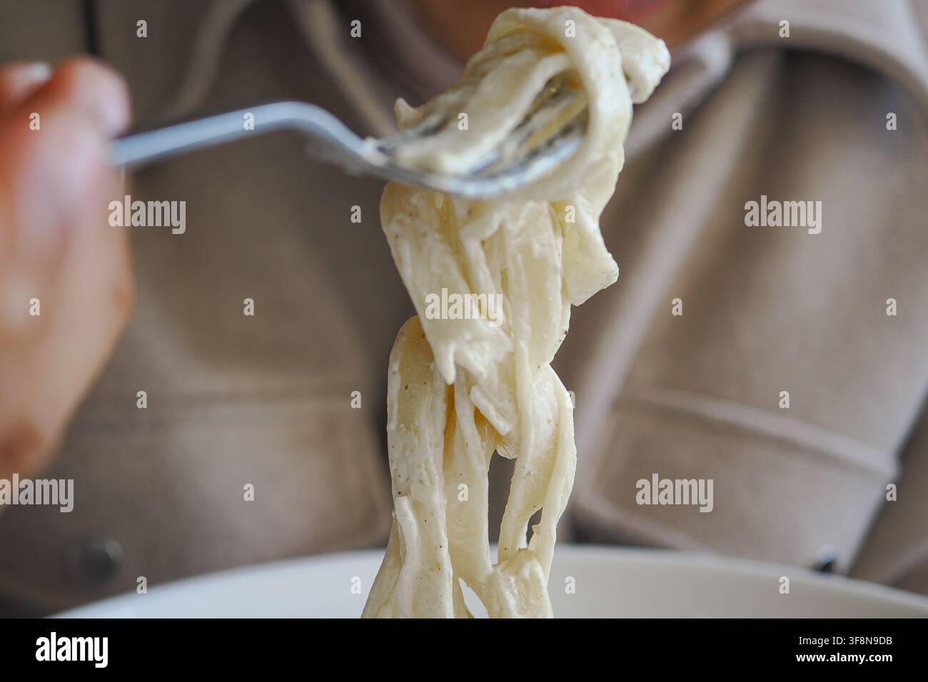 Mangiare la pasta con una forchetta in un ristorante Foto Stock