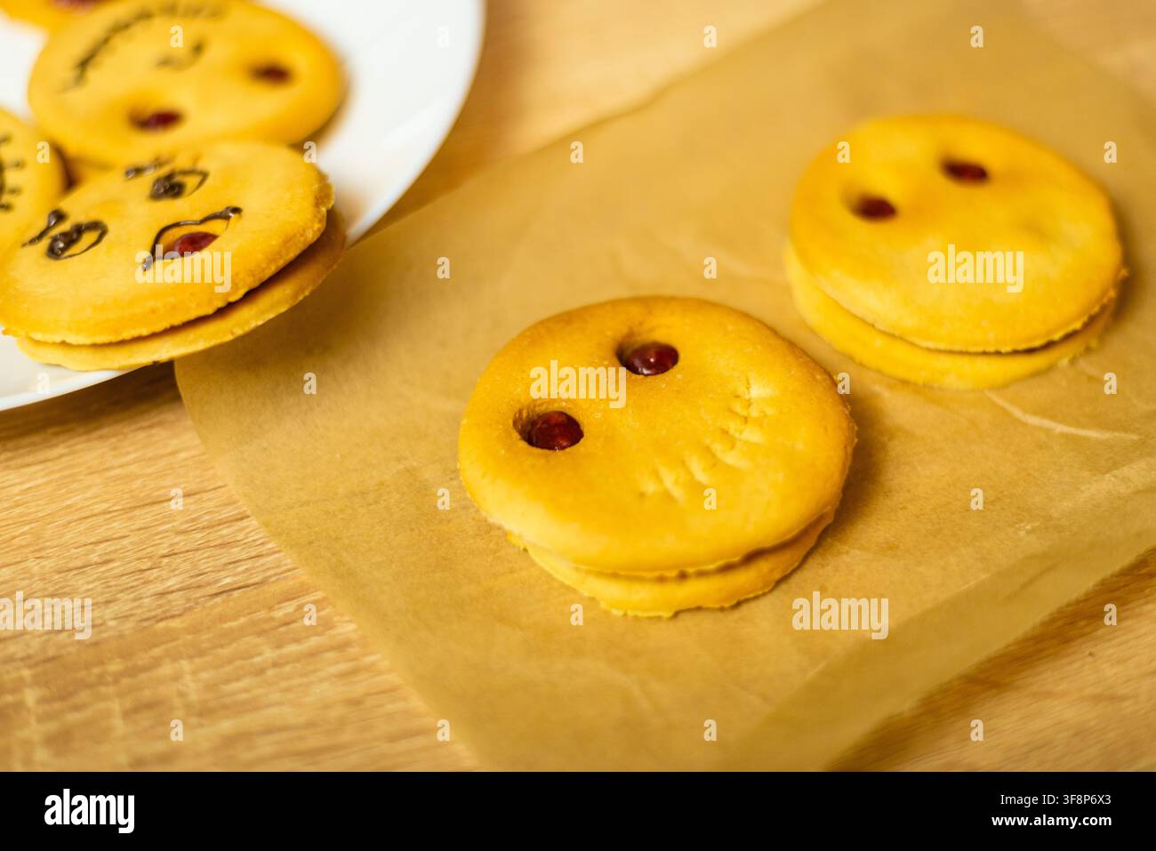 Prima piano dell'aggiunta di espressioni facciali spaventose a biscotti festivi su un bancone di cucina in legno all'aperto Foto Stock
