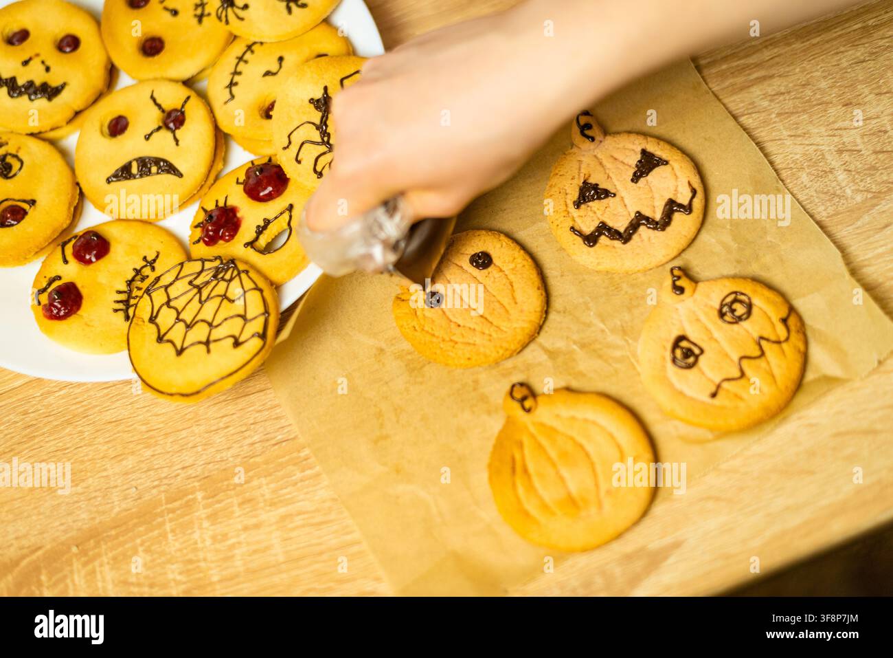 Prima vista di una sac à poche che crea espressioni spaventose su biscotti shortbread fatti in casa su un tavolo da cucina Foto Stock