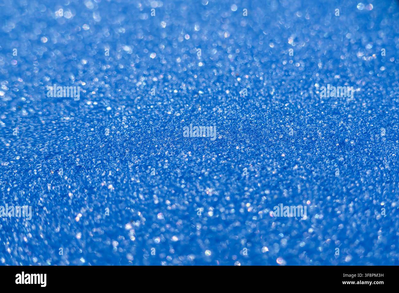 Una texture blu scintillante con profondità di campo ridotta che crea un effetto bokeh e riflessi luccicanti, sfondo astratto festivo che evoca celebrazioni Foto Stock