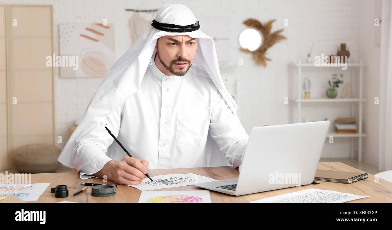 Uomo arabo concentrato in abiti tradizionali che pratica la calligrafia con una penna a pennello e guarda un laptop, Fusione di arte tradizionale e tecnologia moderna Foto Stock