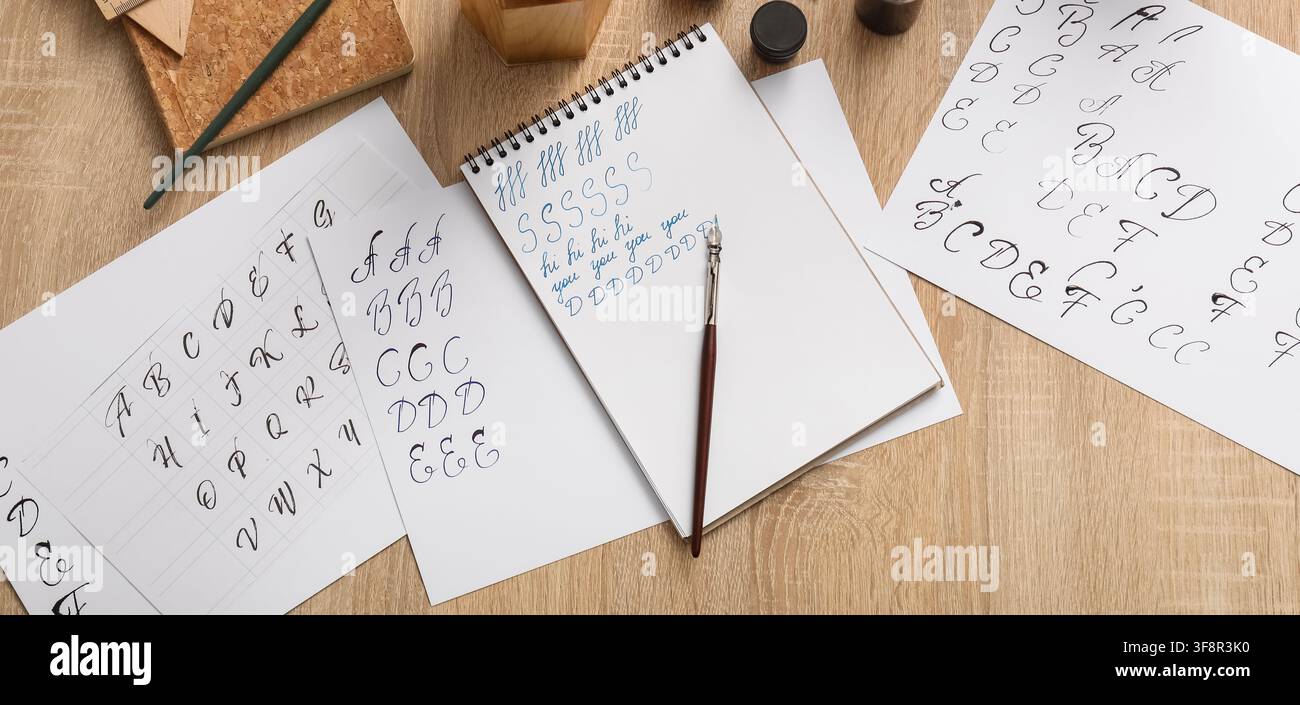 Pratica di calligrafia con una penna stilografica e inchiostro su carta, apprendimento di una scrittura elegante e di una calligrafia su una scrivania di legno Foto Stock