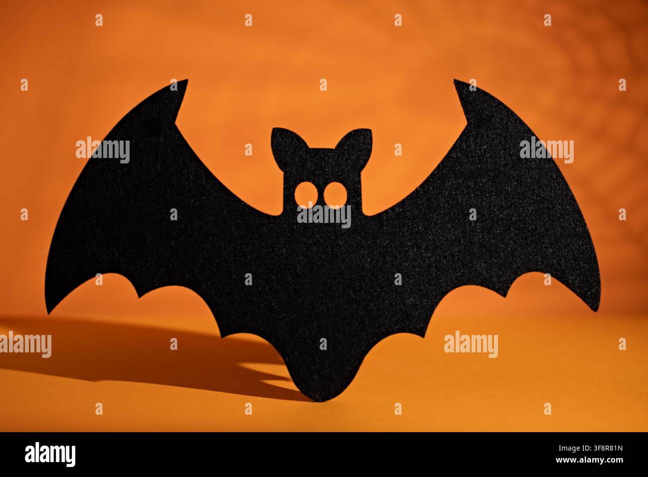Silhouette di grande pipistrello nero centrata su sfondo arancione per invito da poster per festa di Halloween o design stagionale spaventoso Foto Stock