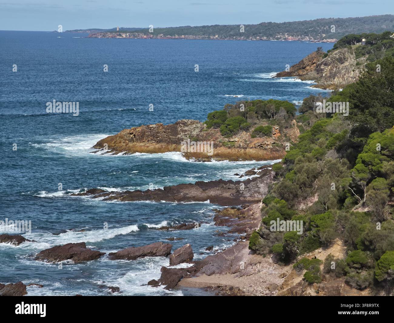 Costa rocciosa drammatica con onde dell'oceano e scogliere boschive lungo la Sapphire Coast in Australia Foto Stock