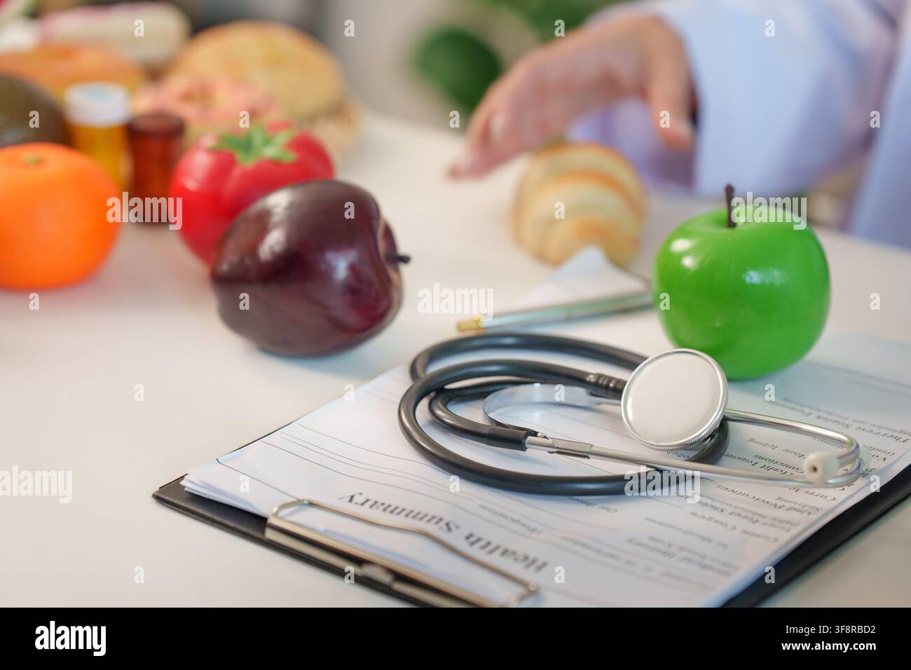Stetoscopio su clipboard di riassunto sanitario nell'ufficio di un consulente nutrizionale con frutti freschi Foto Stock