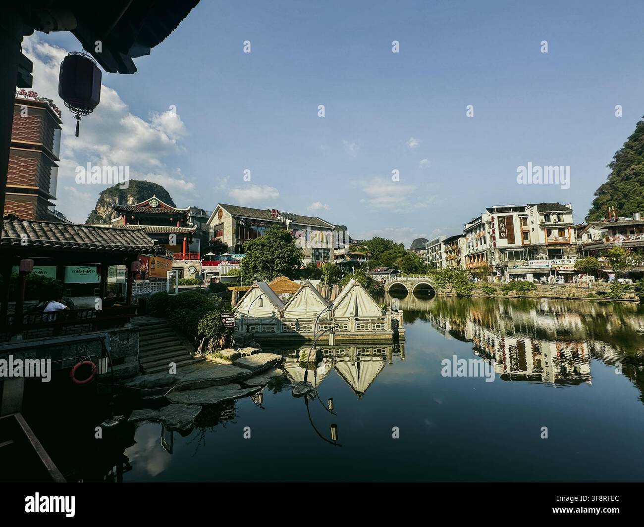 Guilin, Guangxi, Cina - 10 ottobre 2024: Vista del lungofiume della contea di Yangshuo con architettura tradizionale, riflessi calmi del fiume e montagne carsiche Foto Stock