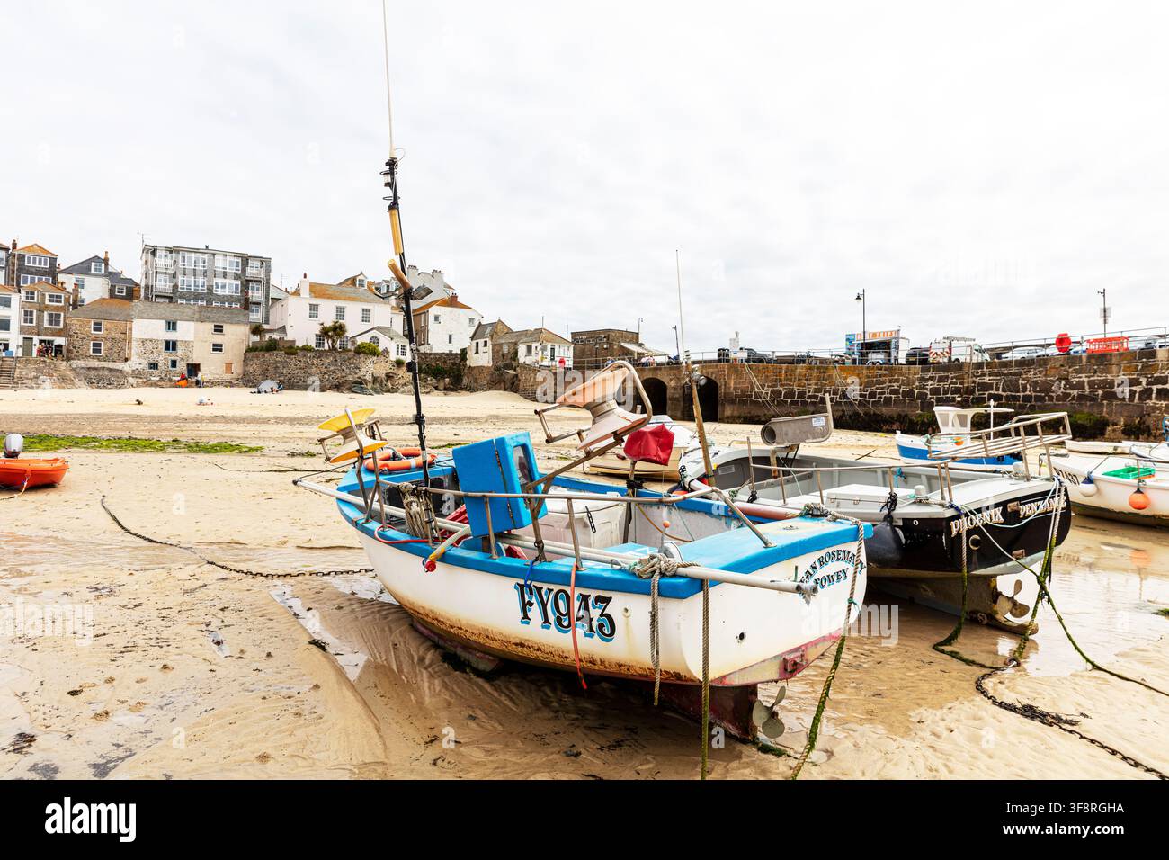 Una scena del porto a bassa marea a St Ives in Cornovaglia, che mostra diverse piccole barche da pesca appoggiate sul fondale sabbioso con corde, boe e alghe sparse Foto Stock