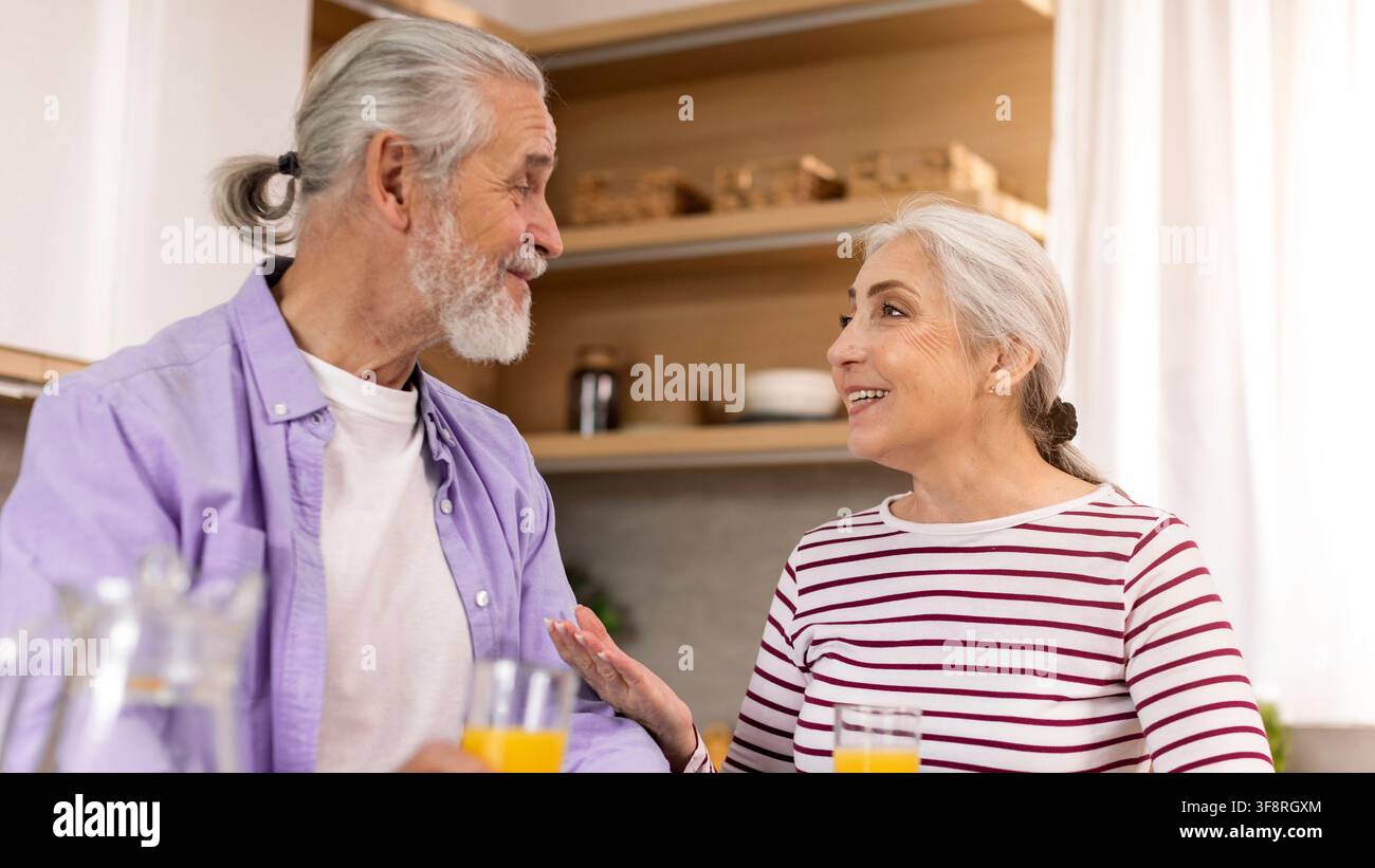 Felice coppia anziana caucasica che conversa's in una cucina elegante, concetto di casa Foto Stock