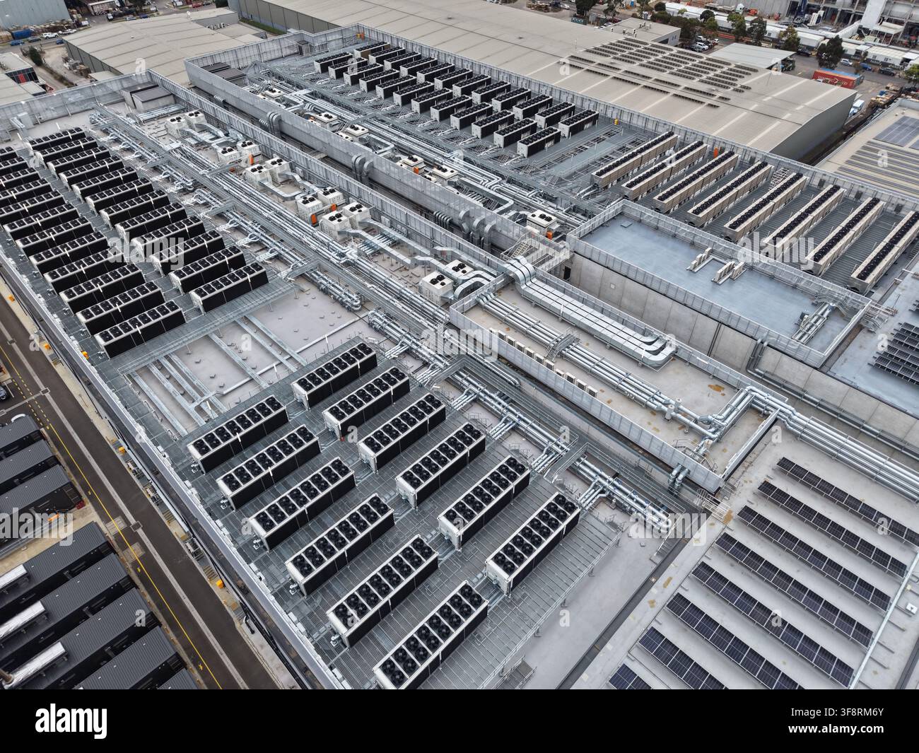 Ampio tetto di data center con estese unità di raffreddamento HVAC, sistemi di ventilazione, infrastruttura di server e pannelli solari ad energia rinnovabile Foto Stock
