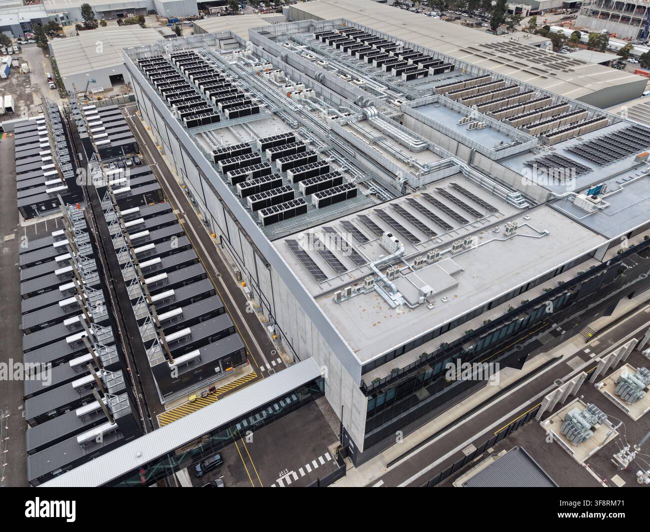 Enorme struttura di data center con file di unità di raffreddamento, moduli server e pannelli solari che supportano l'infrastruttura digitale globale Foto Stock