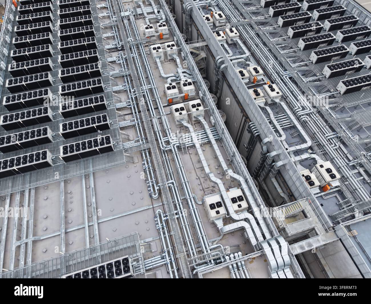 Ampio tetto di un impianto industriale che mostra una rete intricata di sistemi HVAC, unità di climatizzazione, tubi e condotti per il raffreddamento Foto Stock