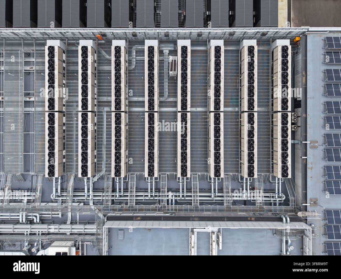 Tetto di un data center con più unità di raffreddamento, sistemi di ventilazione, tubi e pannelli solari per un'energia sostenibile Foto Stock