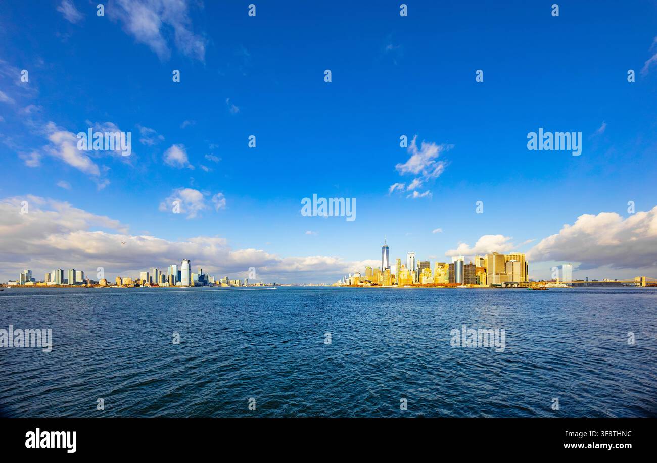 New York, Stati Uniti - 20 novembre 2025: Ampia veduta panoramica dello skyline di Manhattan e Jersey City attraverso il fiume Hudson sotto un cielo blu Foto Stock
