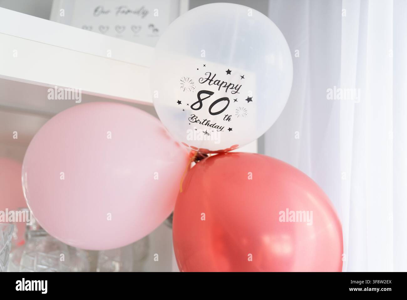 Eleganti palloncini rosa, rossi e bianchi che decorano una casa per una festa di 80° compleanno Foto Stock
