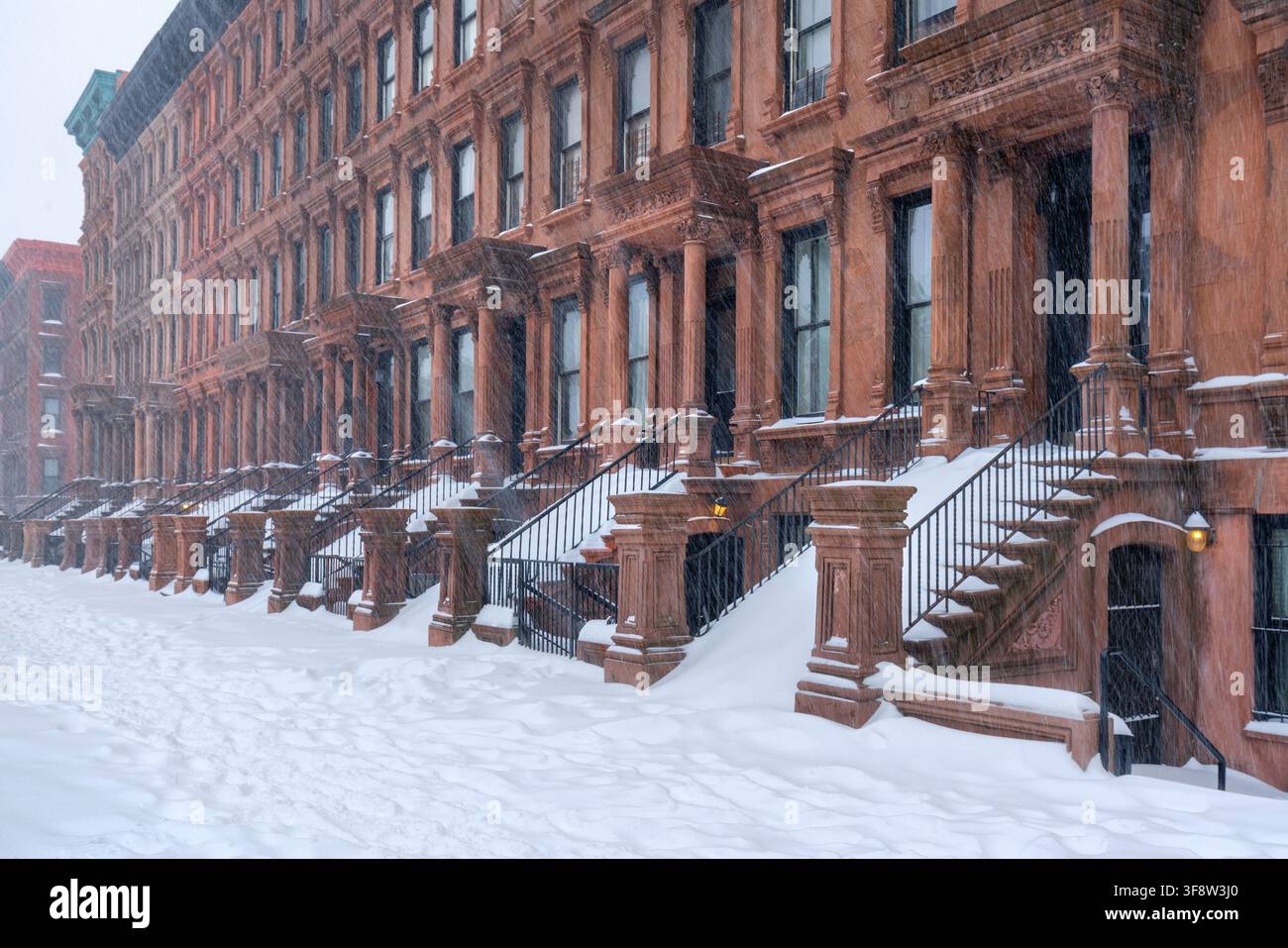 Case a schiera storiche in pietra marrone di Harlem durante una tempesta di neve invernale nel distretto storico di Mount Morris Park, Manhattan, New York City, USA Foto Stock