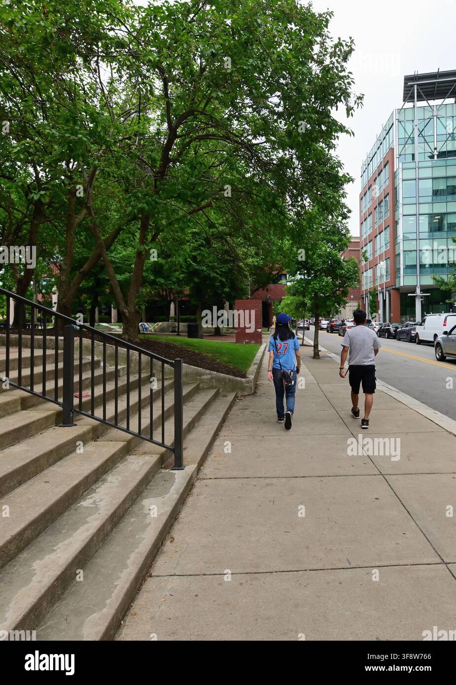 Pittsburgh, Pennsylvania, USA. Una coppia di tifosi del baseball cammina lungo una strada tranquilla nel quartiere di North Shore di Pittsburgh, diretti al PNC Park. Foto Stock