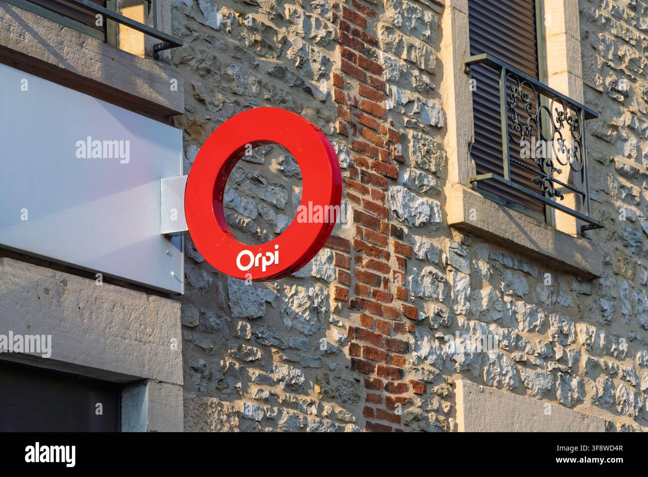 Montrevel-en-Bresse, Francia - 30 luglio 2026: Insegna con logo circolare rosso dell'agenzia immobiliare Orpi montata su una facciata in pietra e mattoni. Foto Stock