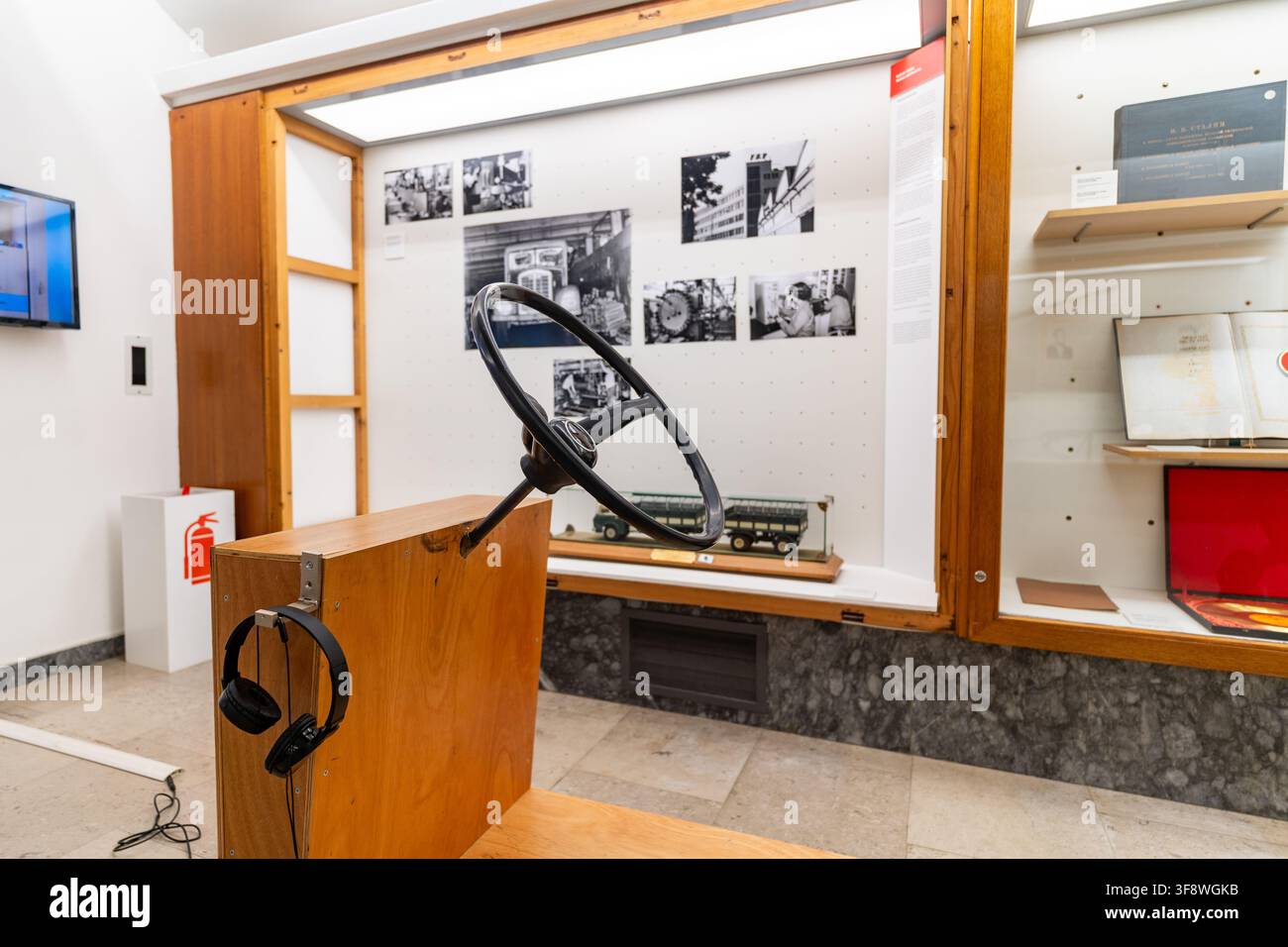 Un display interattivo in un museo presenta un volante vintage montato su un supporto di legno con cuffie per i visitatori. Lo sfondo mette in mostra Foto Stock