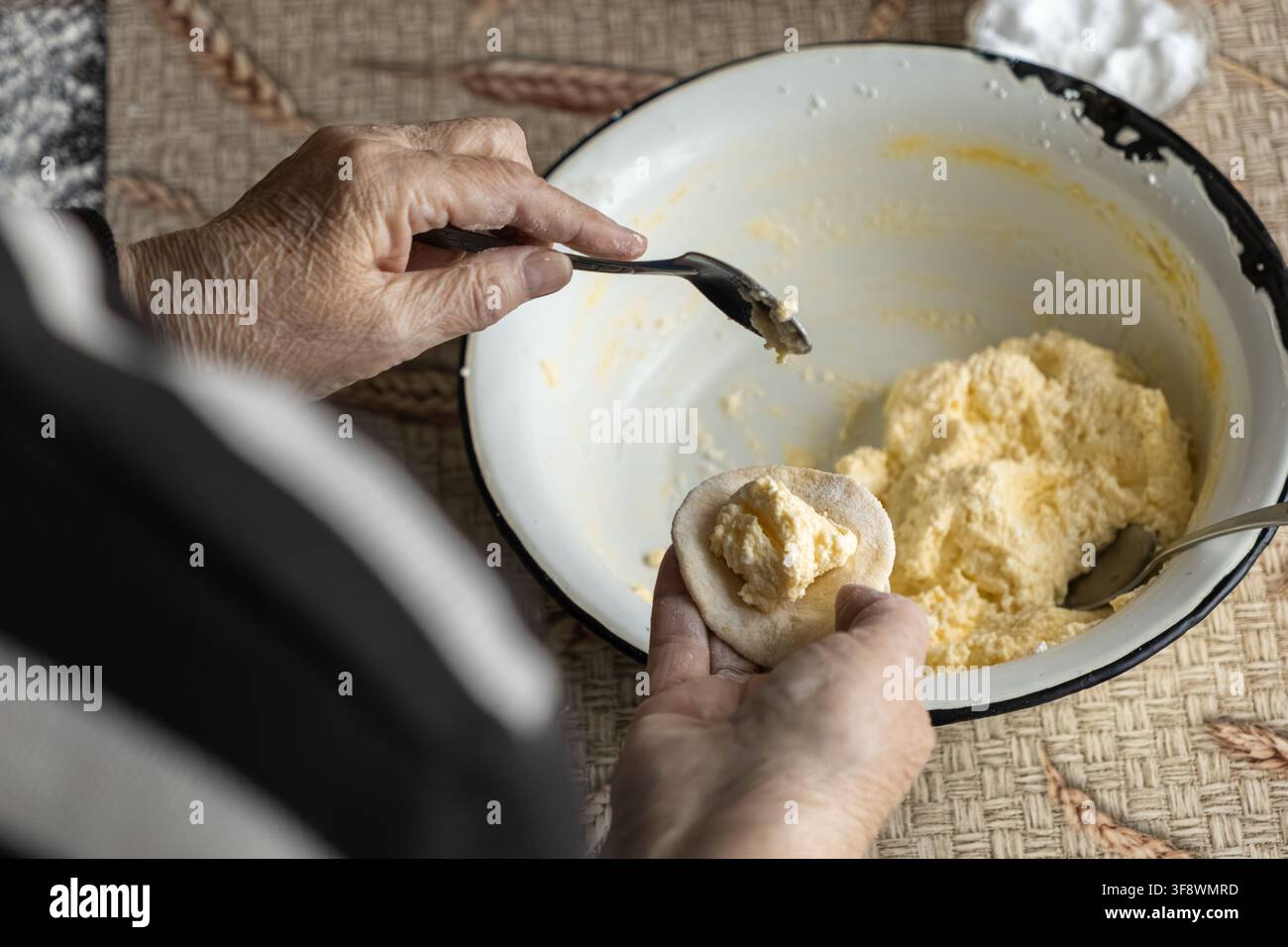 Il panettiere esperto posa un ripieno bianco morbido su cerchi di pane fresco mentre prepara gnocchi rustici, catturando un momento sentito di eredità culinaria Foto Stock