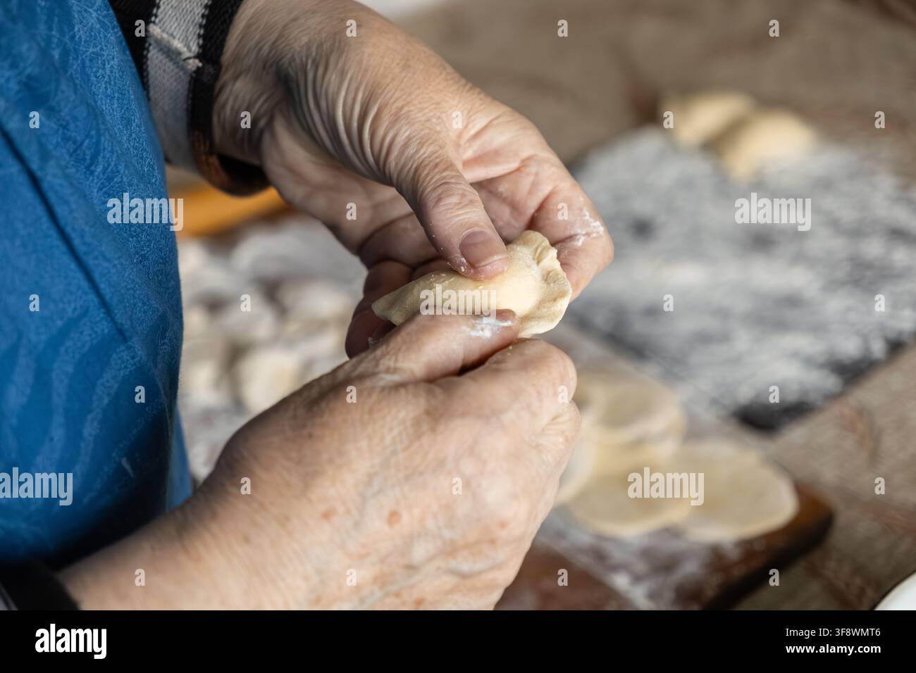 Una persona anziana crea a mano gnocchi freschi in un accogliente ambiente di cucina, evidenziando l'arte nostalgica della preparazione tradizionale dei pasti e la cura Foto Stock