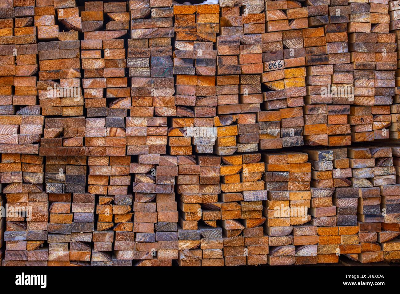 Vista ravvicinata di una pila strettamente impilata di legname grezzo che mostra varie sfumature di marrone e grigio. Un numero "266" scritto a mano è appena visibile sul Foto Stock