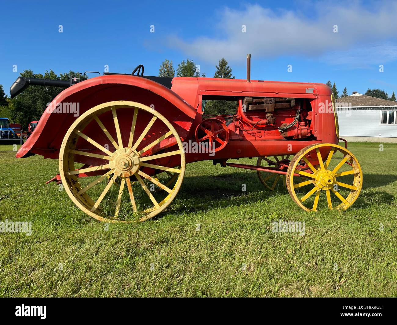 Un trattore rosso vintage del 1938 con grandi ruote in acciaio gialle in mostra sull'erba verde sotto un cielo blu, Plaisance, Quebec, Canada Foto Stock