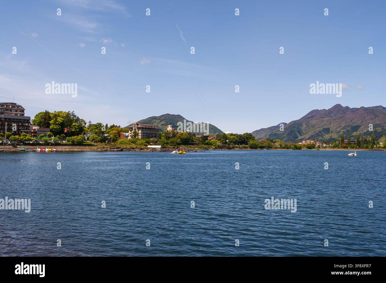 YAMANASHI, GIAPPONE - 5 LUGLIO 2025: Vista panoramica del lungolago di Kawaguchi con hotel e colline verdi nella zona del Monte Fuji durante la stagione estiva. Foto Stock