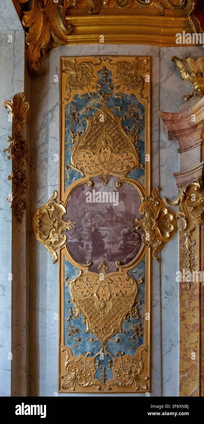 Kempten, Germania - 26 lug 25: Vista verticale di un pannello murale rococò dorato con scene dipinte e decorazioni in marmo pastello all'interno della Residenza di Kempten Foto Stock