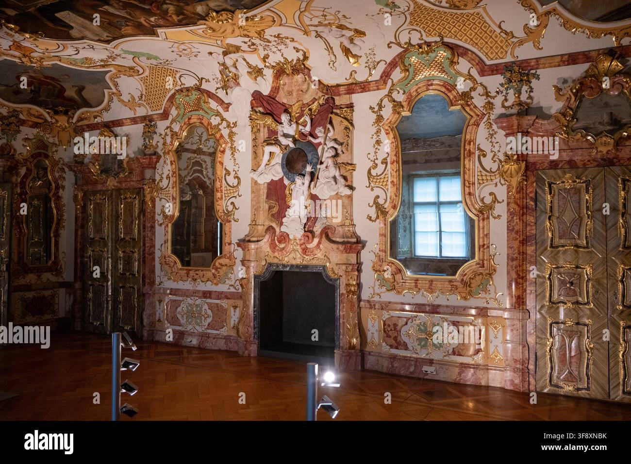 Kempten, Germania - 26 lug 25: Armadio in legno intagliato circondato da dipinti murali rococò dorati e stucco decorativo all'interno della Residenza di Kempten. Foto Stock