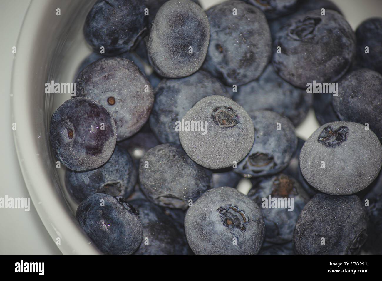 Foto macro di mirtilli freschi congelati con uno strato di brina in una ciotola Foto Stock