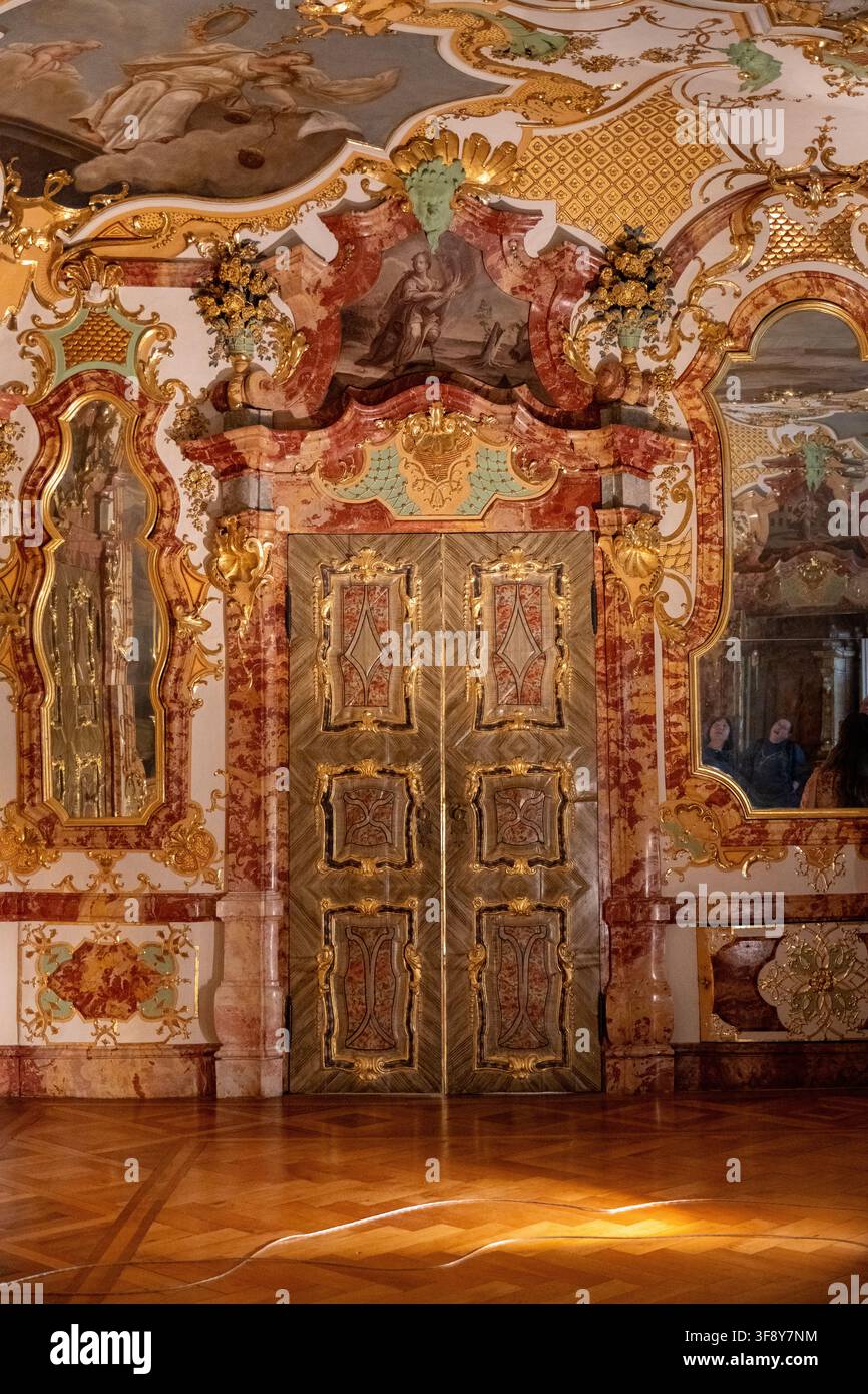 Kempten, Germania - 26 lug 25: Altare a muro rococò riccamente decorato con cherubini, drappeggi rossi e pittura religiosa nella Residenza di Kempten, Germania Foto Stock