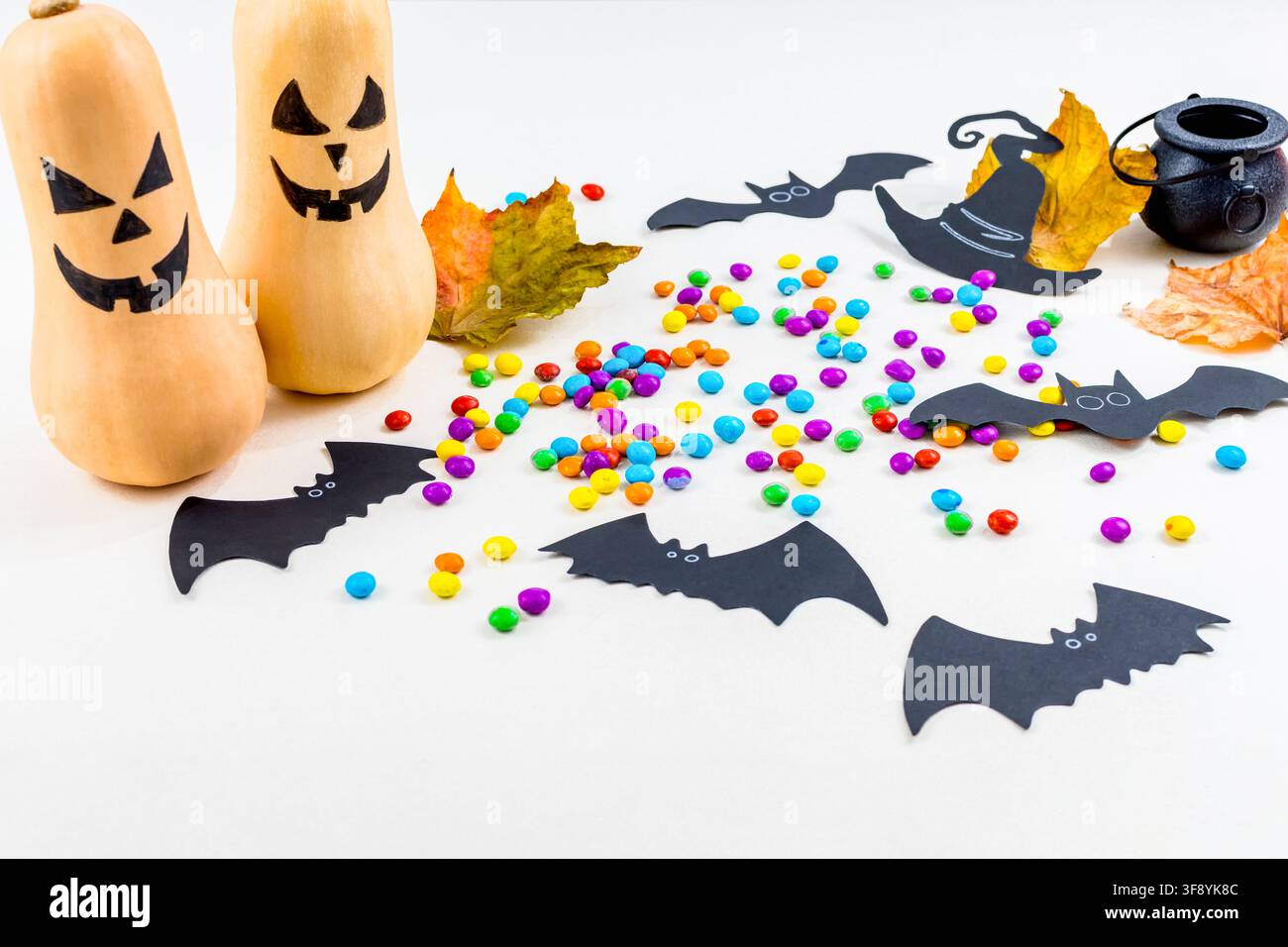 Halloween, zucche, sagome di pipistrelli, granelli colorati, calderone, cappello da strega, su sfondo bianco. Messa a fuoco selettiva. Foto Stock