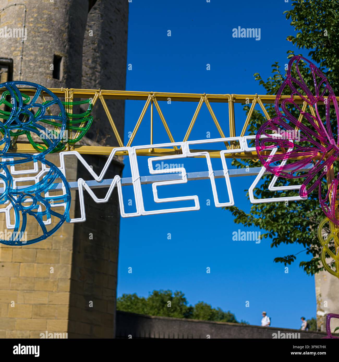 METZ, FRANCIA - 13 AGOSTO 2026 - Insegna al neon di Metz che brilla durante il giorno su un cielo blu terso Foto Stock