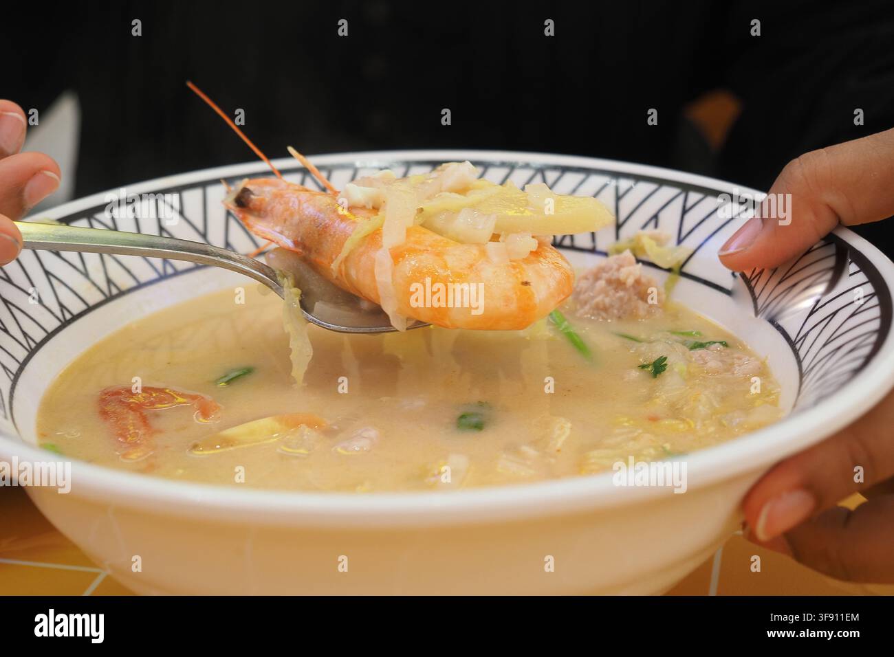 Godendo una ciotola di zuppa di gamberetti in un ristorante locale Foto Stock