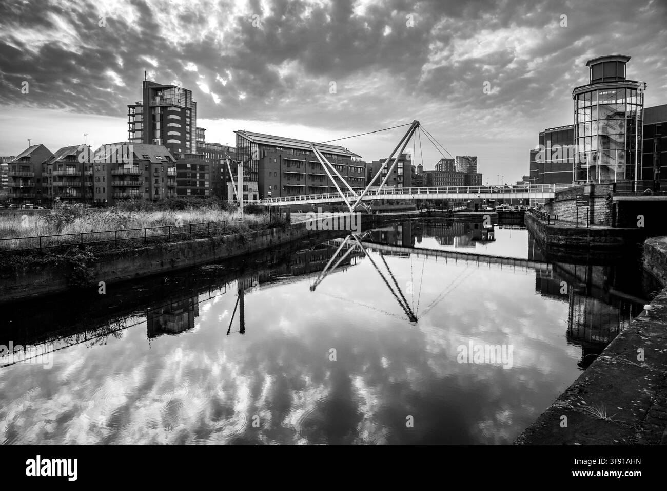 Vista monotona del ponte pedonale Knights Way e del bacino del canale Clarence Dock con riflessi urbani a Leeds Foto Stock