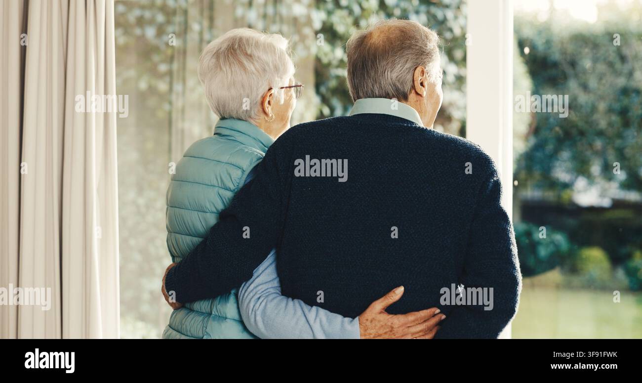 Amore, pensiero e coppia anziana alla finestra con abbraccio, riflessione sulla relazione e memoria in pensione. Schiena, connessione e anziani con abbraccio Foto Stock