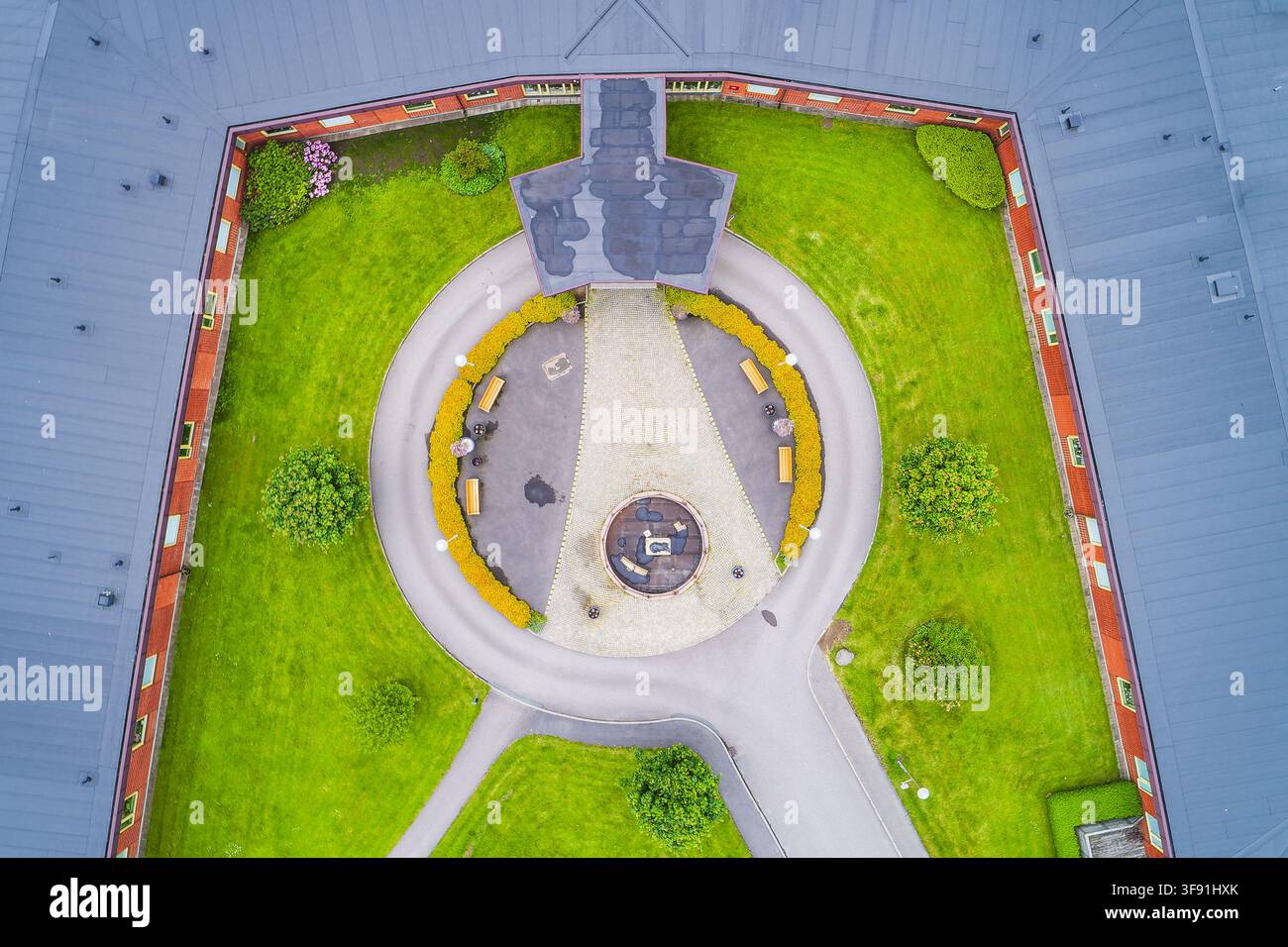 Vista aerea di un cortile circolare con una fontana centrale, circondato da un edificio moderno con tetto grigio e prati verde brillante a Molndal, Västra Götaland Foto Stock