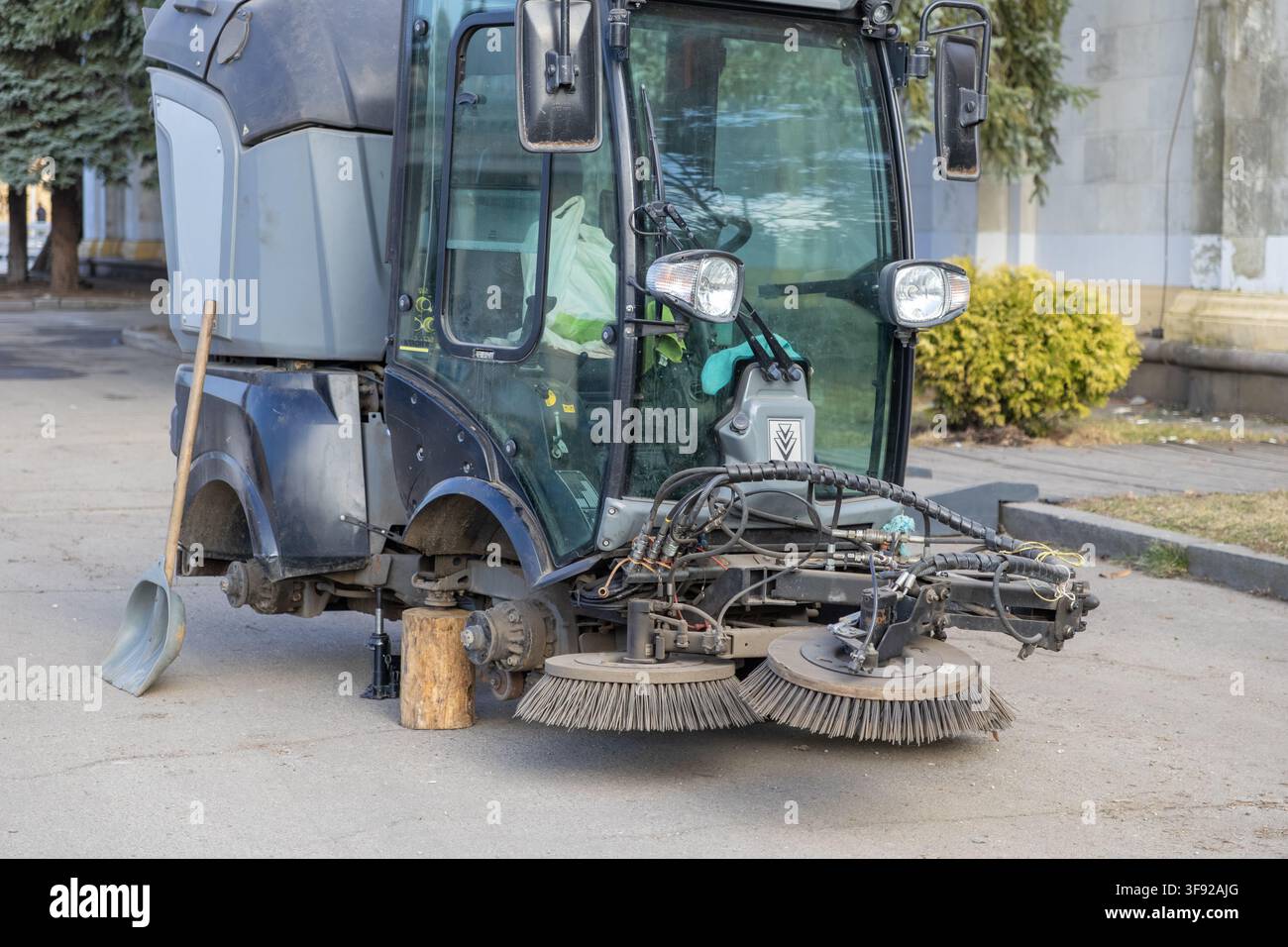 Il veicolo per la pulizia delle strade danneggiato rimane fermo durante la riparazione, evidenziando gli aspetti logistici della manutenzione municipale e la cura essenziale Foto Stock