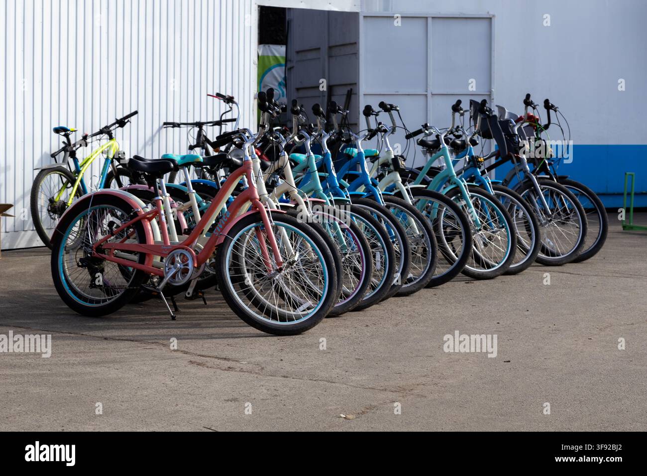 Kyiv, Ucraina - 22 marzo 2026: Diverse biciclette luminose allineate su un terreno lastricato in attesa di ciclisti in un contesto di viaggio estivo, evidenziando tr ecologici Foto Stock