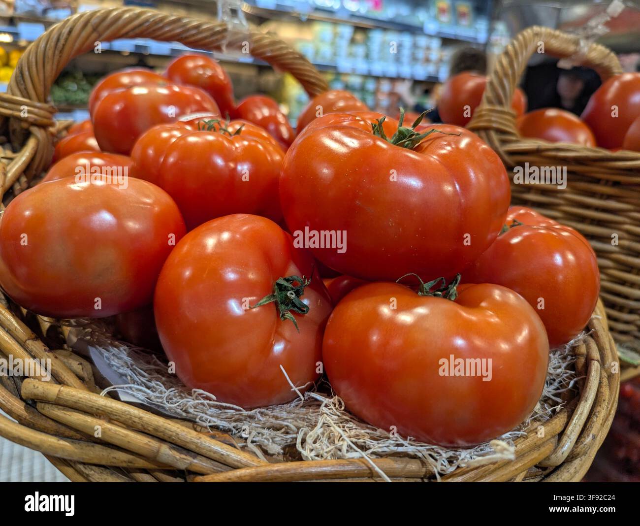 Un grande cesto di vimini pieno di pomodori rossi freschi e maturi a filetto di manzo con forme classiche nervate e arrotondate, a New York, USA. - Immagine stock catturata con smartphone