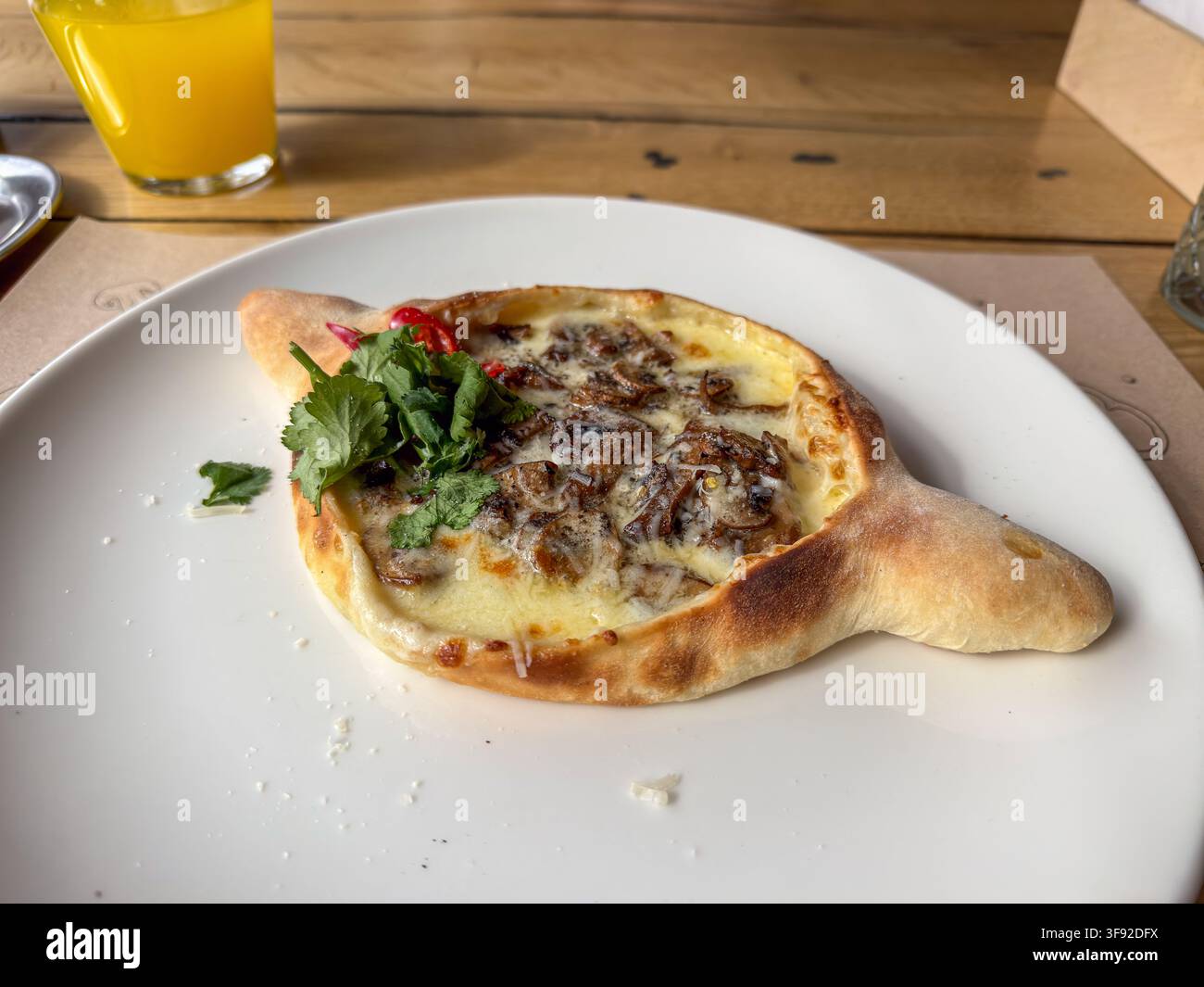 Appetitoso khachapuri aperto con funghi saporiti e formaggio fuso, guarnito con coriandolo e peperoncino, che cattura l'essenza di un piatto sano Foto Stock