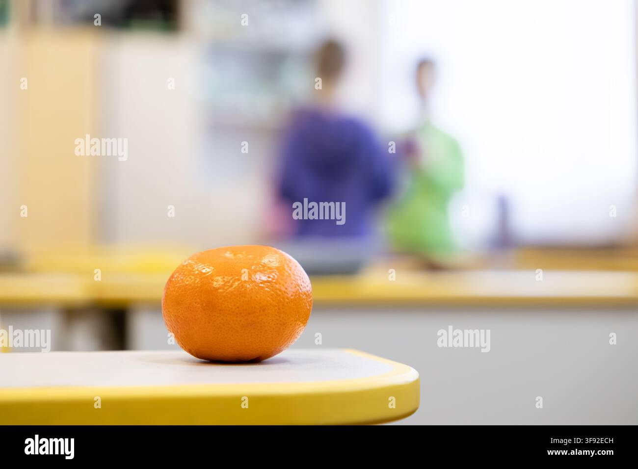 Frutti di agrumi brillanti posizionati su un tavolo in un contesto di scuola primaria, che trasmettono uno stile di vita sano e l'attenzione alla nutrizione per i bambini in un ambiente educativo Foto Stock