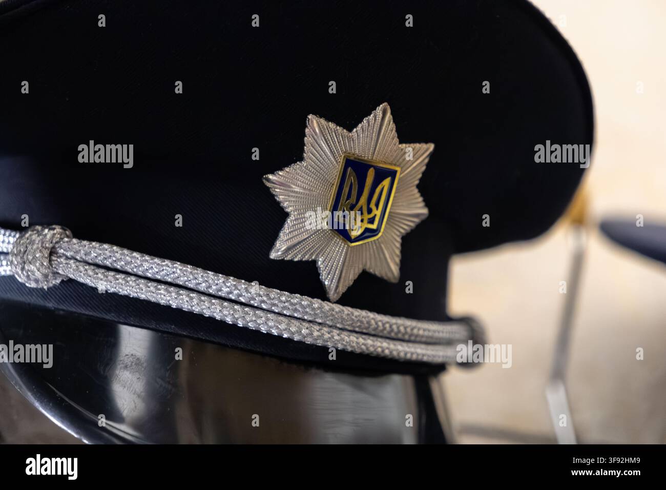 Kyiv, Ucraina – 20 marzo 2026: Copricapo professionale di un funzionario di polizia adornato con un intricato distintivo a stella d’argento e un tridente, che riflette Foto Stock