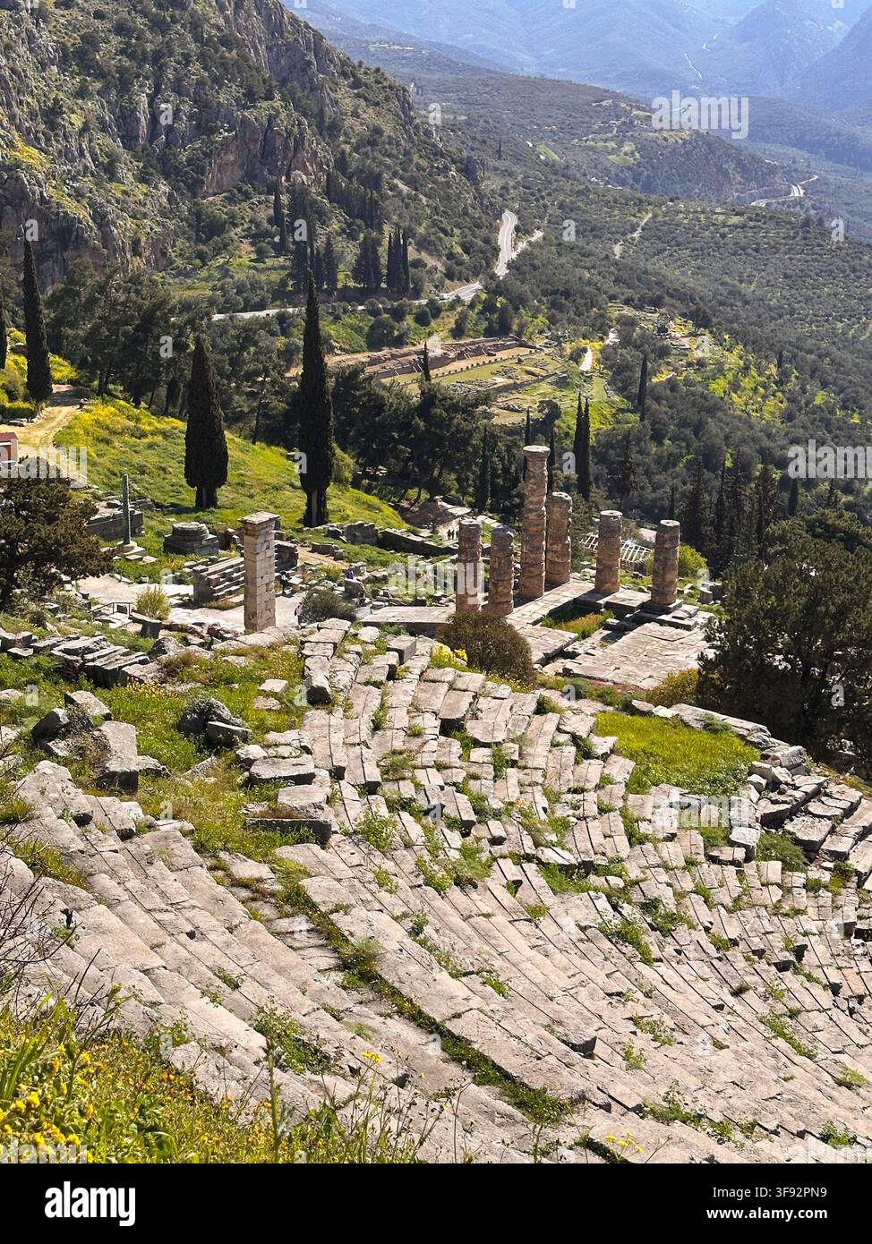 Ampia veduta del teatro antico e delle rovine del tempio circondati dal paesaggio montuoso di Delfi, Grecia Foto Stock