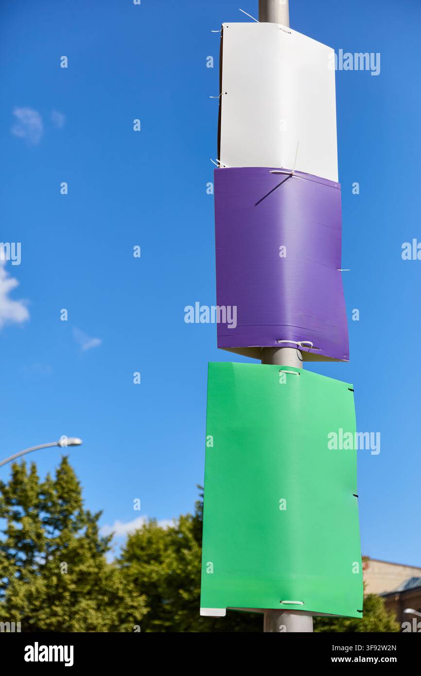 Tre poster elettorali completamente vuoti – bianco, viola e verde – montati uno sopra l'altro su un lampione contro un cielo blu di Berlino. La Su non stampata Foto Stock
