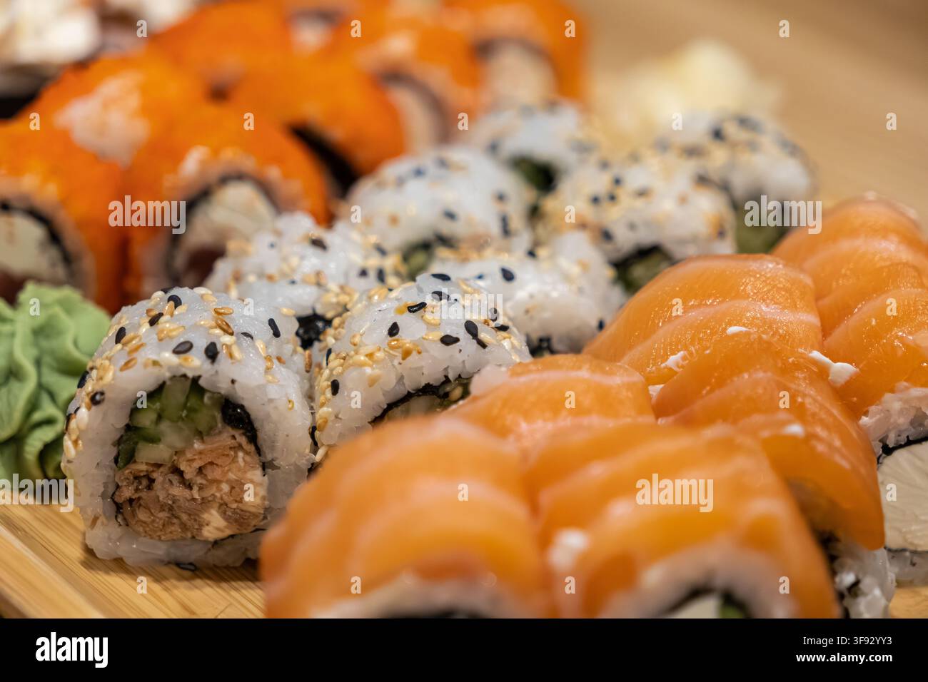 Deliziosa selezione di sushi arrotolato a mano servito su una tavola di legno con zenzero e wasabi, che riflette ingredienti di qualità premium per un'esperienza culinaria raffinata Foto Stock