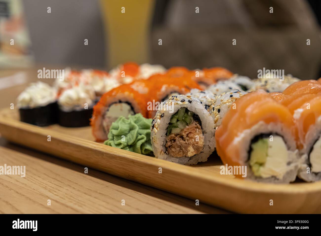 Deliziosa varietà di rotoli di sushi freschi serviti su una tavola di legno, con salmone e formaggio cremoso, offrendo un'estetica elegante per una fo professionale Foto Stock