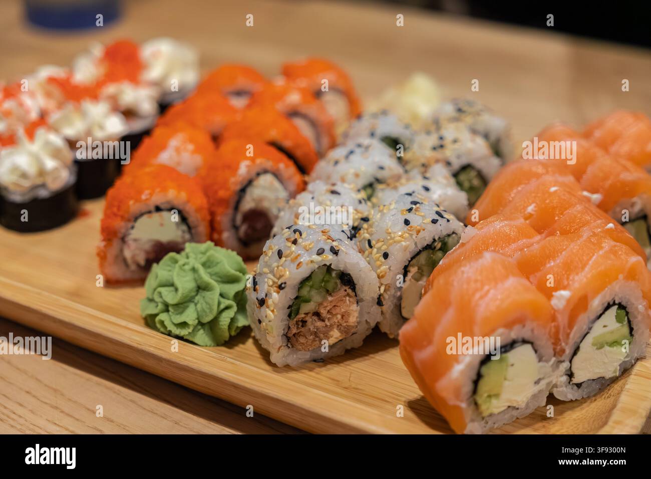 Selezione varia di rotoli di sushi maki appena preparati serviti su una tavola di bambù, che evidenziano texture ricche e sapori autentici per una cena di alta qualità Foto Stock