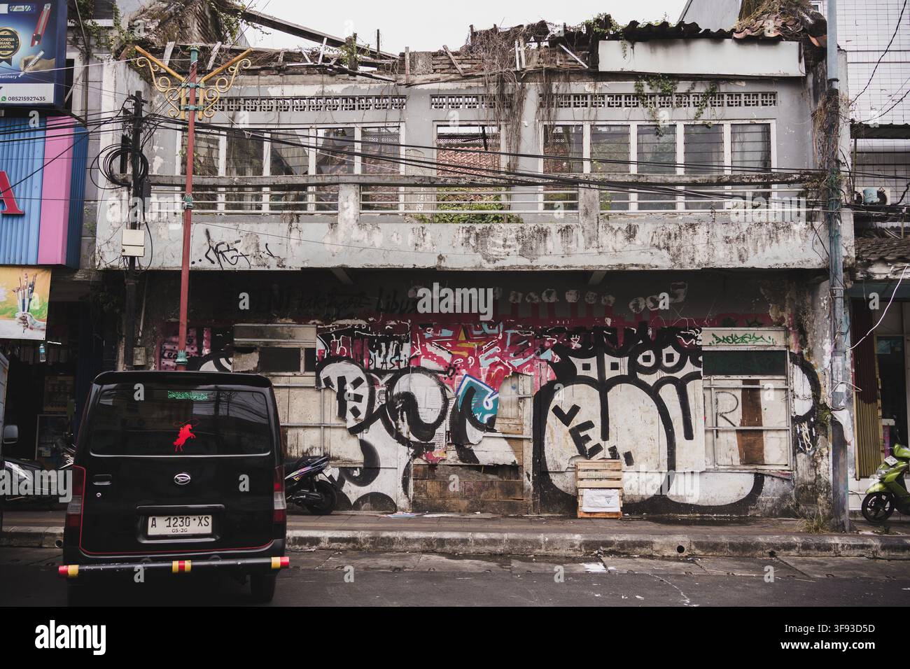 TANGERANG, INDONESIA - 28 GIUGNO 2026: Un edificio decadente e abbandonato con finestre rotte, un tetto crollato e pareti coperte di graffiti vivaci Foto Stock