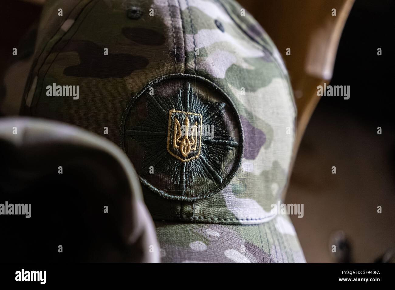 Kyiv, Ucraina - 15 marzo 2026: Cappello mimetico tattico con una toppa a tridente ricamata dettagliata che simboleggia la sovranità e la difesa dello stato Foto Stock